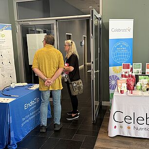Ausstellerstand von Celebrate und EndoZip auf den Interdisziplinären Adipositas Tagen 2026 in München. Zwei Teilnehmer:innen am erkunden des Stands.
